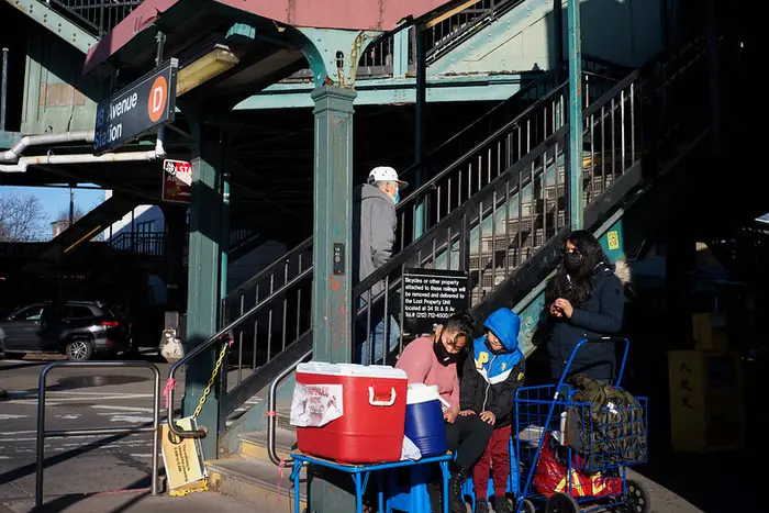 someone sells tamales beneath an elevated subway station